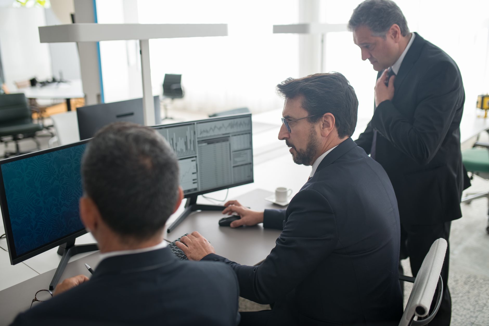 Pessoas trabalhando diante de telas de computador em um escritório de trading, ilustrando os negócios regionais de corretagem que Karamanis vai liderar.
