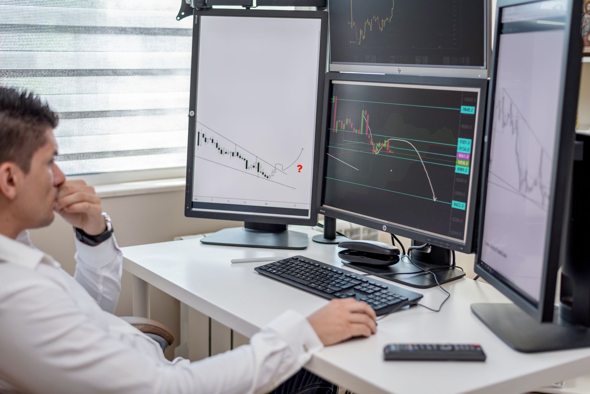 Trading screens in an office illustrate the systems affected by IC's brand and data consolidation.