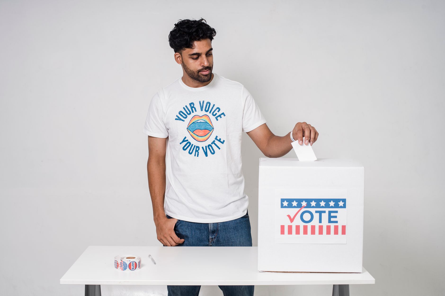 Una persona consulta una boleta en papel junto a un teléfono que muestra información sobre elecciones locales.