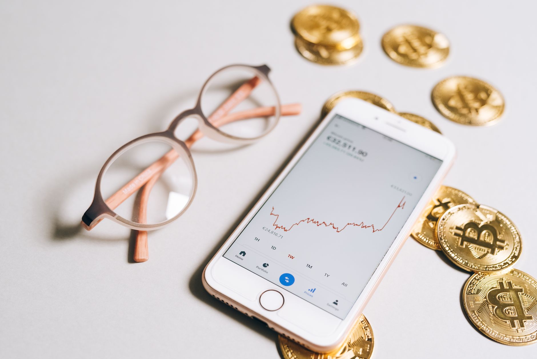 Barras de ouro ao lado de um smartphone que exibe um gráfico de ativo tokenizado