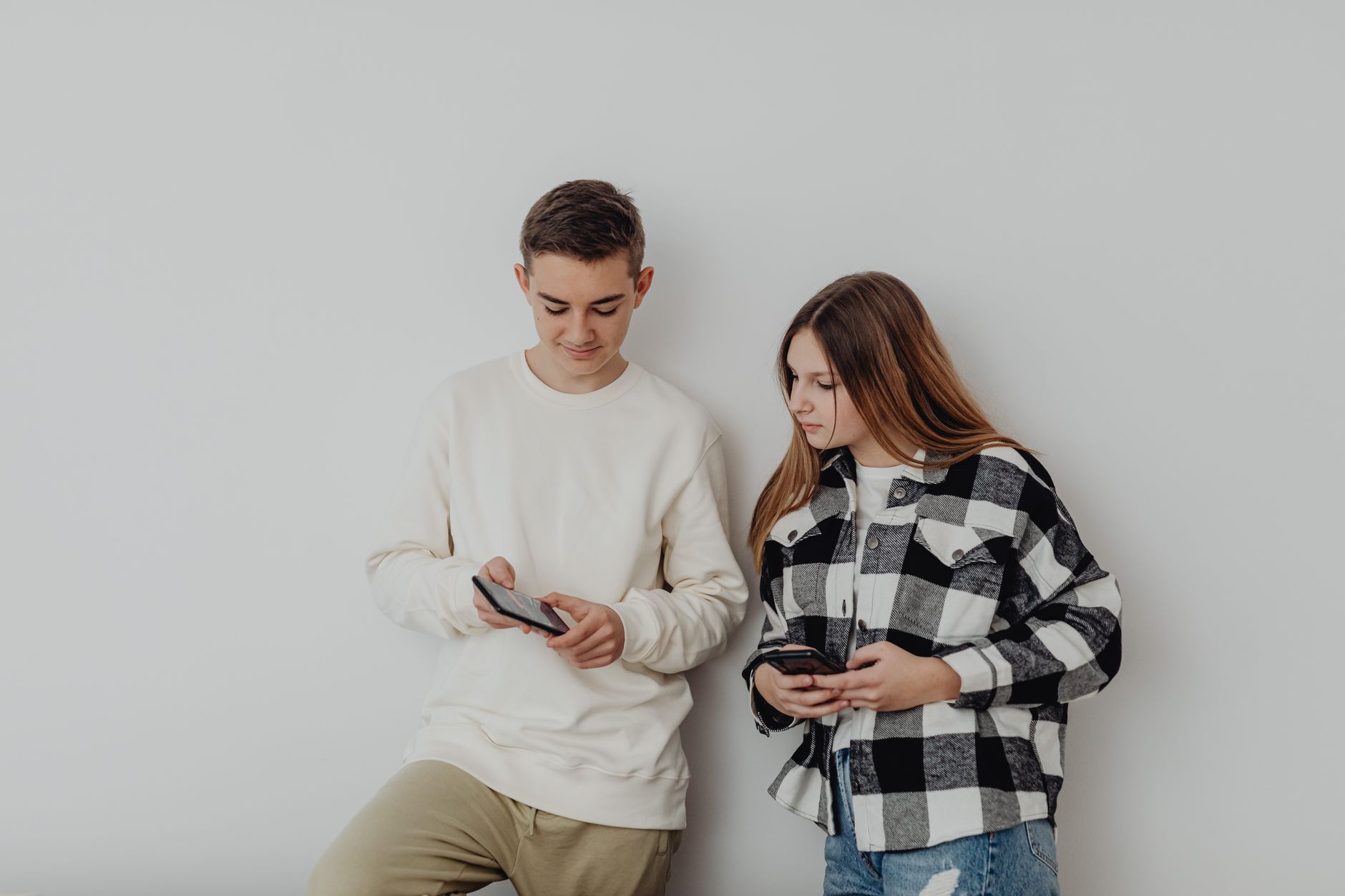 Teenager using a smartphone to view an investing account, with a parent nearby